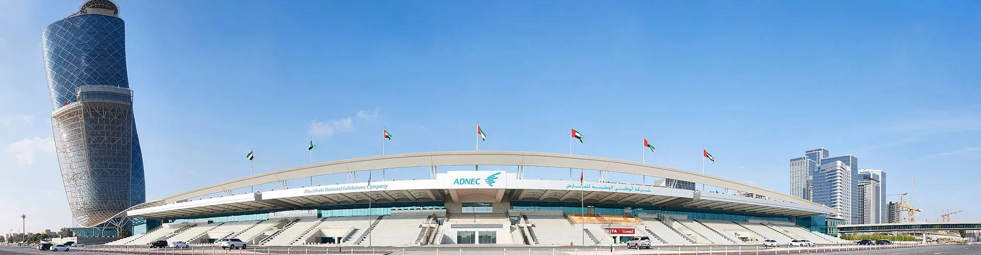 ADNEC main entrance with UAE flags and the Capital Gate tower